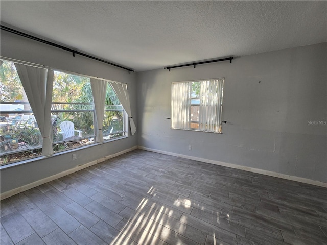 unfurnished room featuring a textured ceiling, a healthy amount of sunlight, and hardwood / wood-style flooring