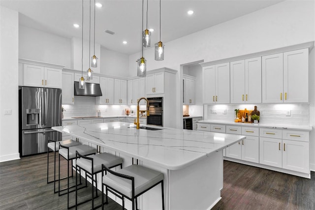 kitchen with white cabinetry, a center island with sink, appliances with stainless steel finishes, dark hardwood / wood-style floors, and decorative light fixtures