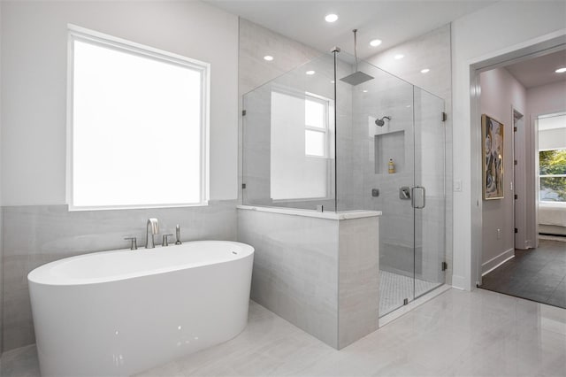 bathroom featuring tile walls and independent shower and bath