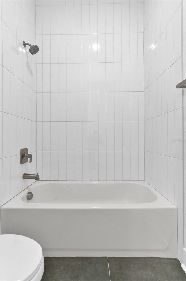 bathroom with tile patterned flooring, tiled shower / bath combo, and toilet