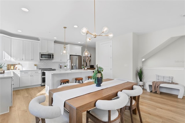 dining space featuring light wood-type flooring and an inviting chandelier