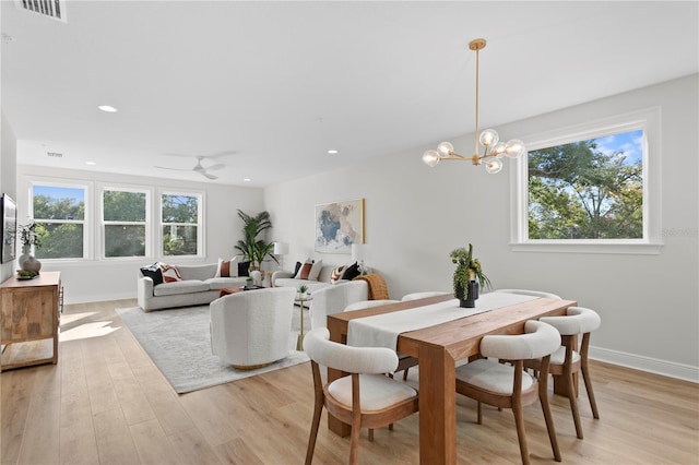 dining space with ceiling fan with notable chandelier and light wood-type flooring