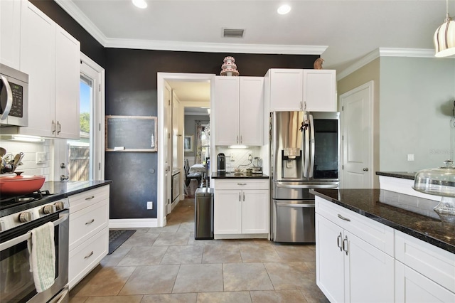 kitchen featuring dark stone countertops, crown molding, stainless steel appliances, and white cabinets