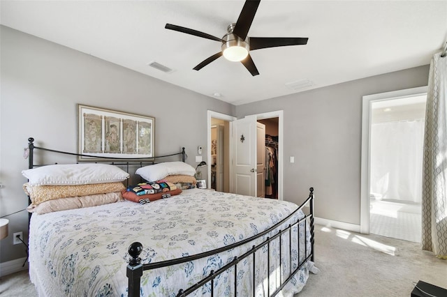 bedroom with light carpet, a walk in closet, a closet, and ceiling fan