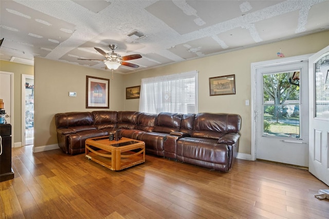 living room featuring a textured ceiling, light wood-type flooring, and ceiling fan