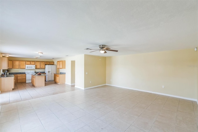 unfurnished living room with sink, ceiling fan, and light tile patterned floors