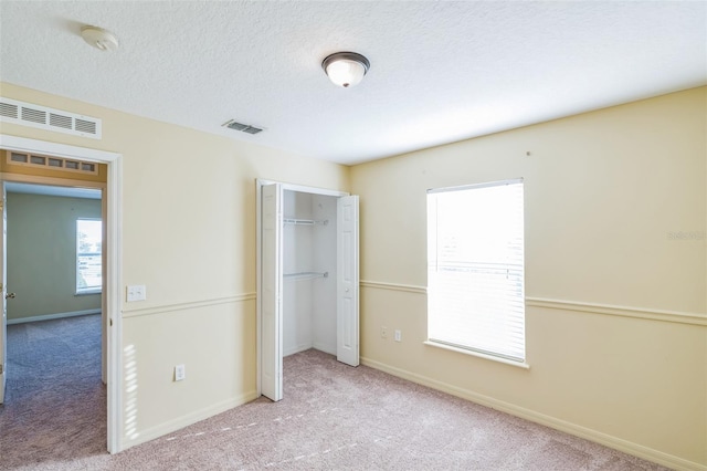 unfurnished bedroom with a closet, light carpet, and a textured ceiling