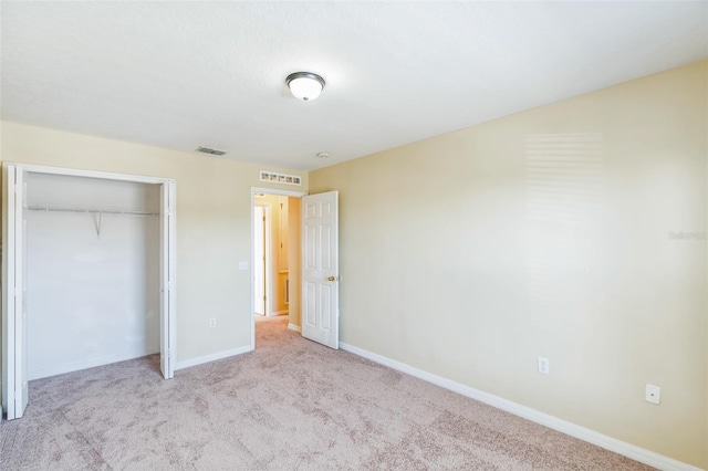 unfurnished bedroom featuring a closet and light colored carpet