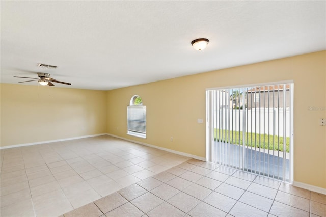 empty room with light tile patterned floors, a wealth of natural light, and ceiling fan