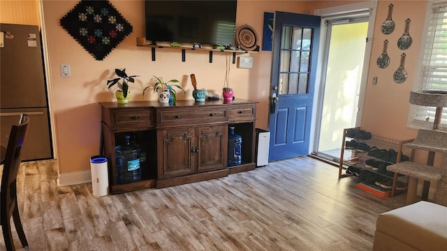 bar with stainless steel refrigerator and light hardwood / wood-style floors