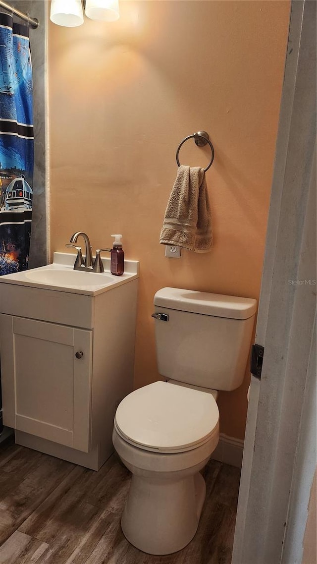 bathroom featuring wood-type flooring, vanity, toilet, and walk in shower