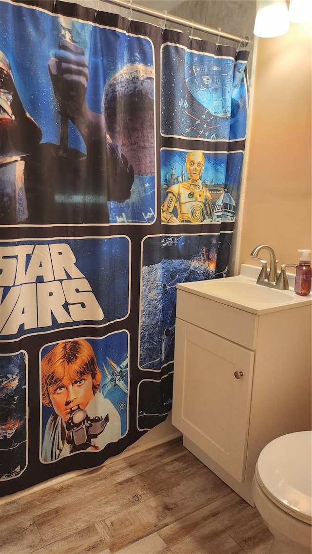 bathroom featuring hardwood / wood-style flooring, curtained shower, toilet, and sink