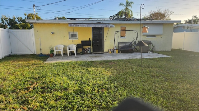 rear view of house featuring a lawn and a patio