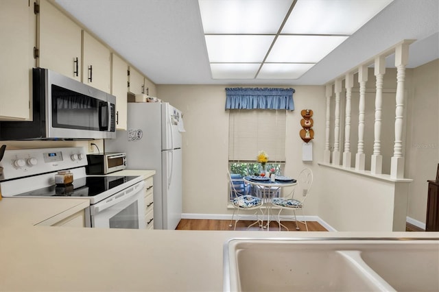 kitchen with cream cabinetry, hardwood / wood-style floors, white range with electric cooktop, and sink