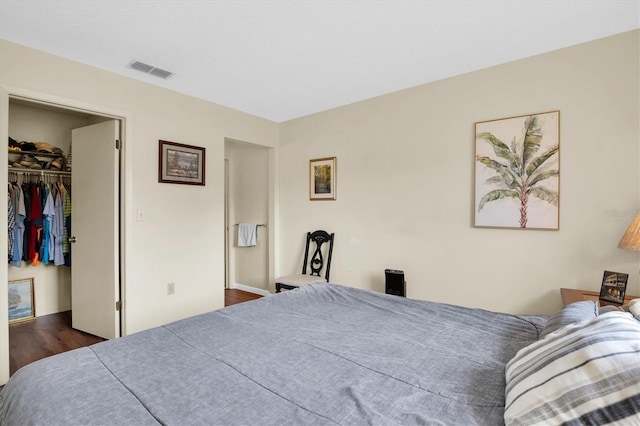 bedroom with a spacious closet, a closet, and dark hardwood / wood-style floors