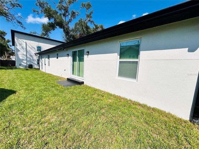 back of property with a lawn and stucco siding