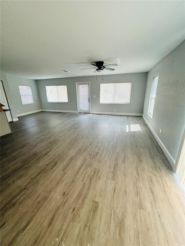 unfurnished living room with baseboards, a ceiling fan, and wood finished floors