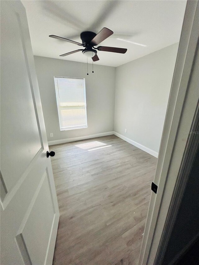 spare room with baseboards, a ceiling fan, and wood finished floors