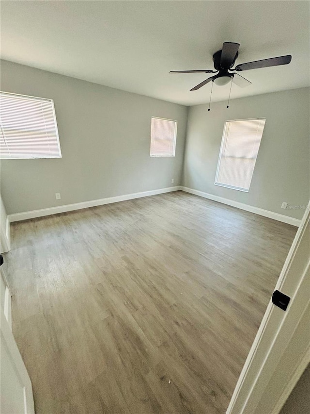 empty room with baseboards, a ceiling fan, and wood finished floors