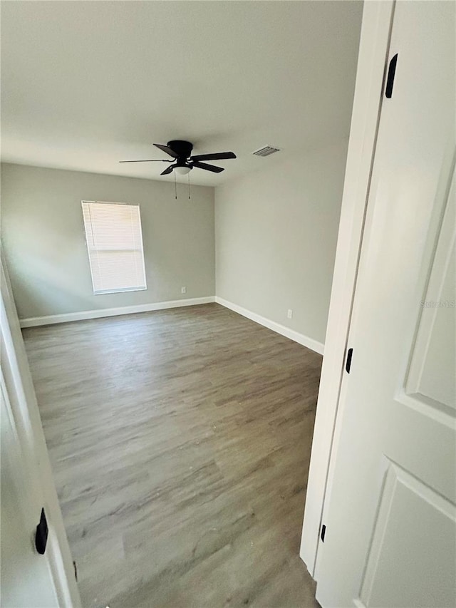 spare room with visible vents, baseboards, ceiling fan, and wood finished floors