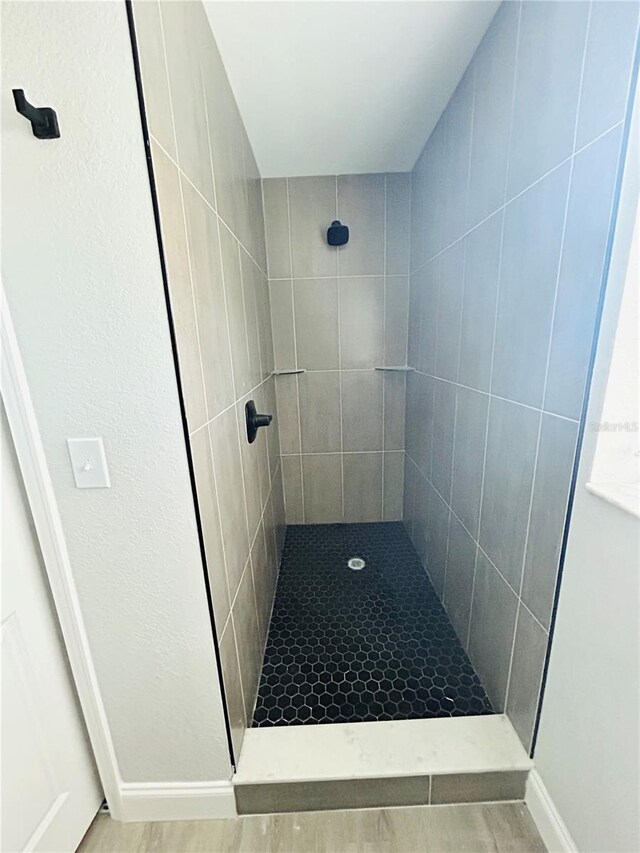 full bathroom with baseboards and a tile shower