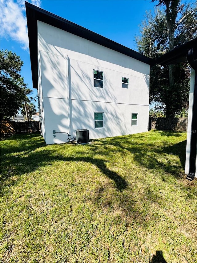 view of home's exterior featuring a lawn, fence, and central AC unit