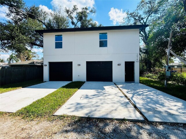 exterior space featuring an attached garage, stucco siding, driveway, and fence