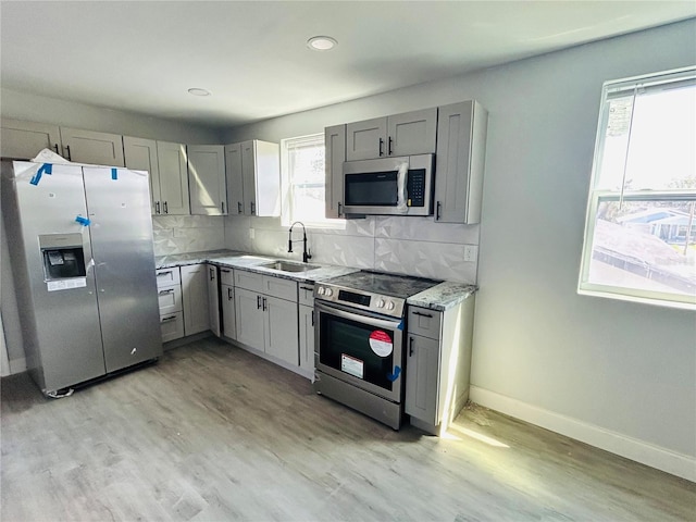 kitchen with gray cabinets, sink, appliances with stainless steel finishes, and light hardwood / wood-style flooring