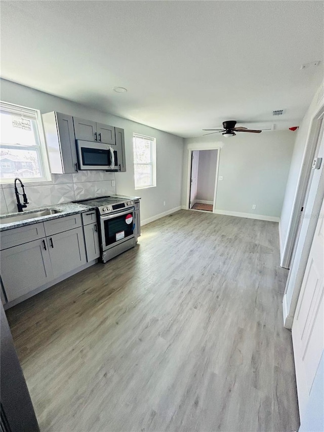 kitchen with gray cabinetry, sink, light wood-type flooring, appliances with stainless steel finishes, and ceiling fan