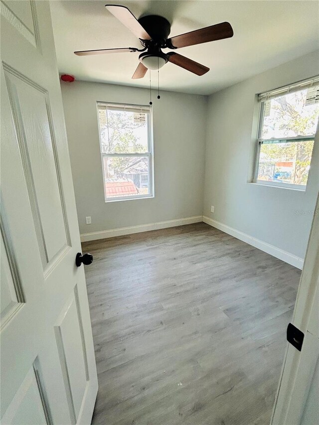unfurnished room with baseboards, a ceiling fan, and wood finished floors