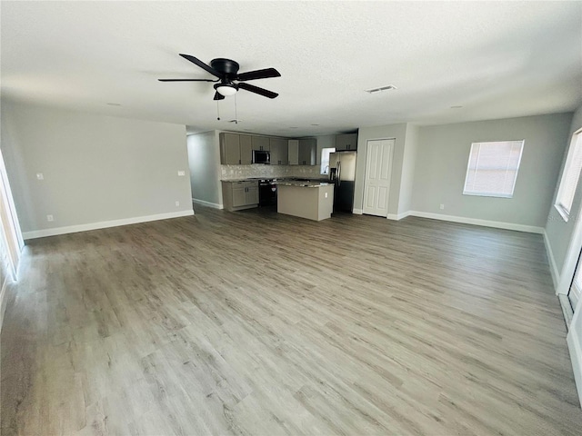 unfurnished living room featuring visible vents, a ceiling fan, baseboards, and wood finished floors