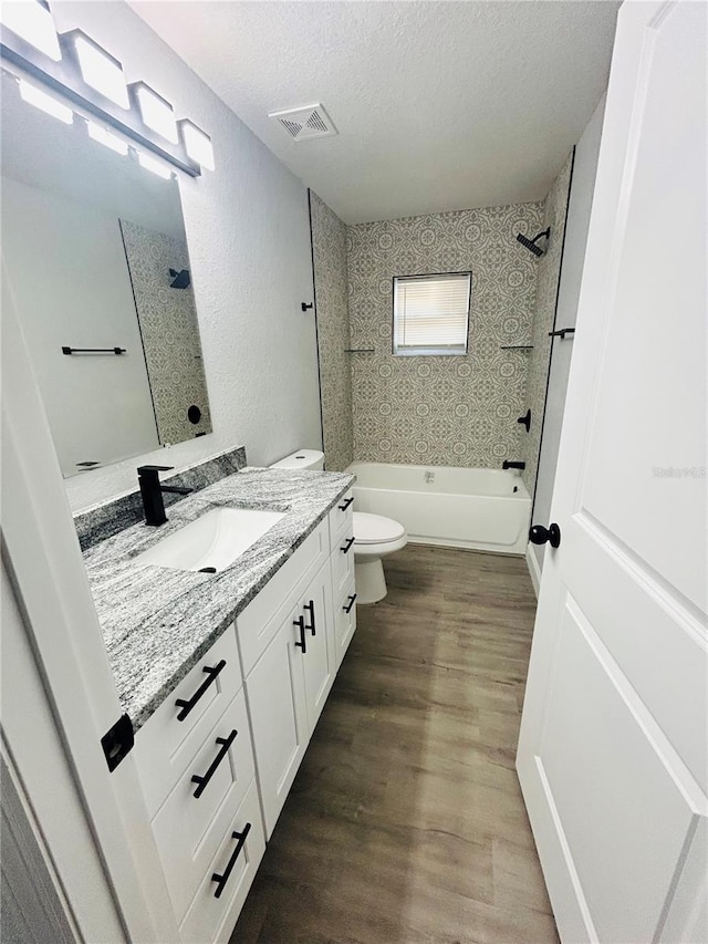 bathroom with visible vents, vanity, wood finished floors, toilet, and a textured ceiling