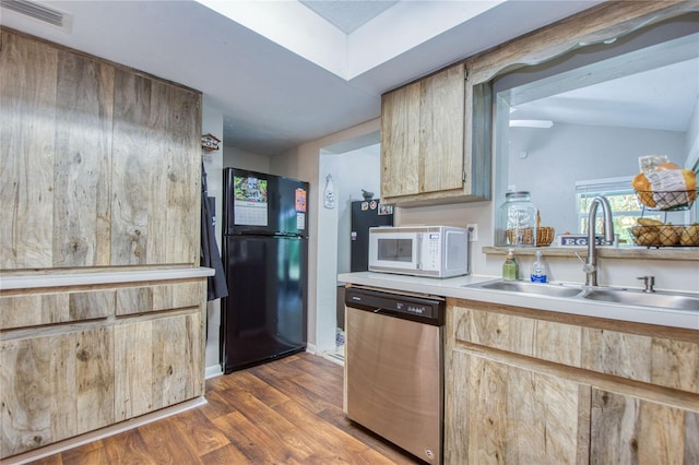 kitchen featuring sink, dishwasher, black fridge, vaulted ceiling, and dark wood-type flooring