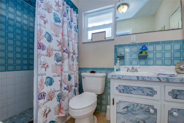 bathroom with tile walls, toilet, vanity, curtained shower, and tile patterned floors