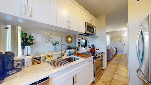 kitchen with light tile patterned floors, appliances with stainless steel finishes, sink, and white cabinets