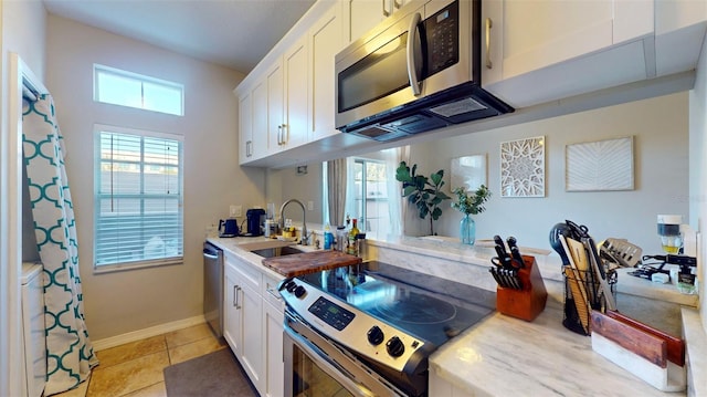 kitchen featuring sink, appliances with stainless steel finishes, white cabinetry, and light tile patterned floors