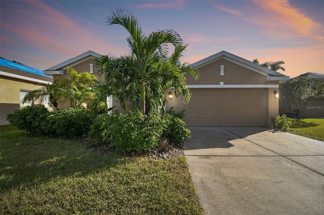 ranch-style home featuring a garage and a lawn