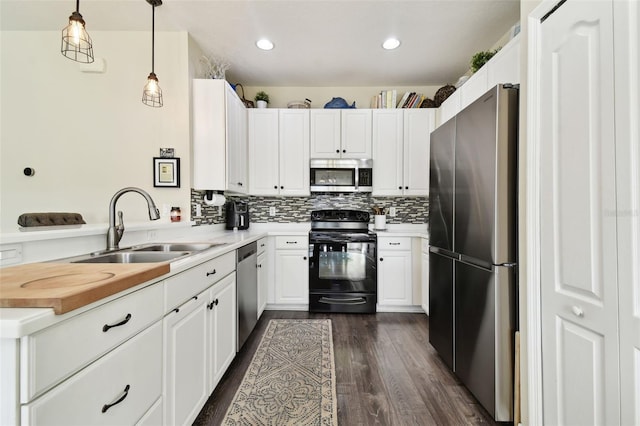 kitchen featuring stainless steel appliances, white cabinetry, sink, and decorative light fixtures