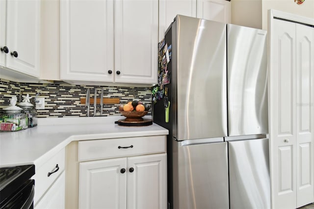 kitchen with decorative backsplash, stainless steel refrigerator, and white cabinets