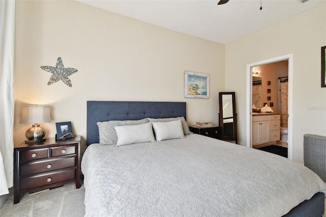 bedroom with ceiling fan, ensuite bath, and light carpet