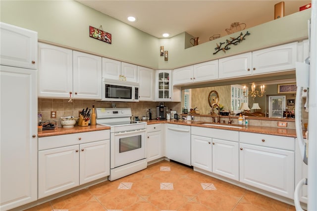 kitchen with white appliances, light tile patterned flooring, sink, backsplash, and white cabinets