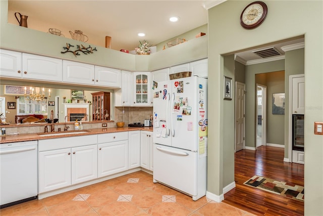 kitchen featuring white appliances, sink, light wood-type flooring, white cabinetry, and crown molding