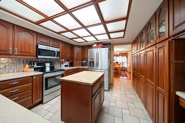 kitchen featuring a kitchen island, appliances with stainless steel finishes, decorative backsplash, and butcher block counters