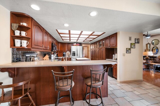 kitchen featuring appliances with stainless steel finishes, kitchen peninsula, tasteful backsplash, and a breakfast bar