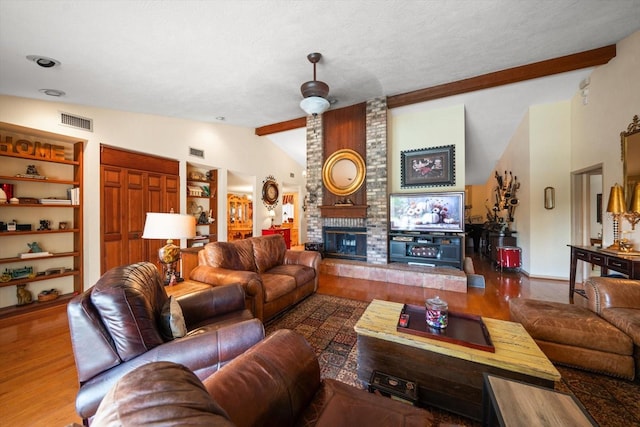 living room with vaulted ceiling with beams, hardwood / wood-style floors, a brick fireplace, built in features, and a textured ceiling