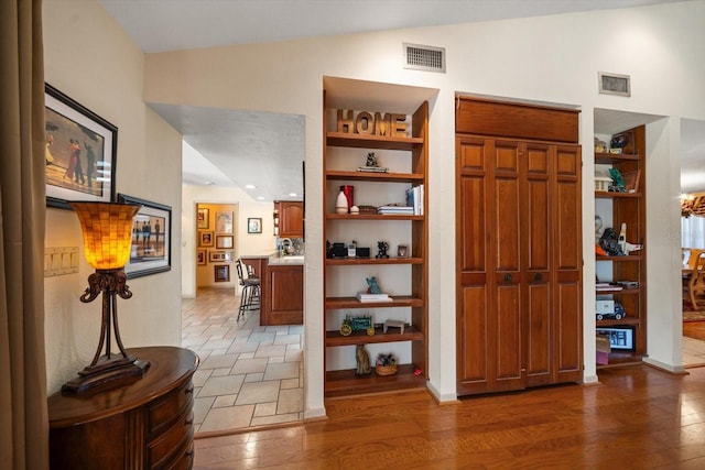 hallway featuring dark wood-type flooring, vaulted ceiling, and built in shelves