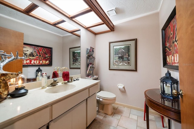 bathroom featuring vanity, tile patterned floors, a textured ceiling, and toilet