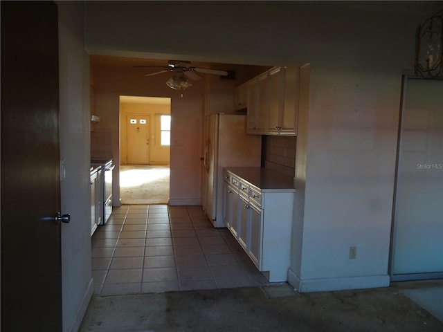 kitchen featuring white cabinets, ceiling fan, light tile patterned flooring, and white refrigerator