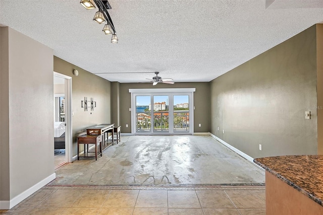 unfurnished living room featuring a textured ceiling, rail lighting, and ceiling fan