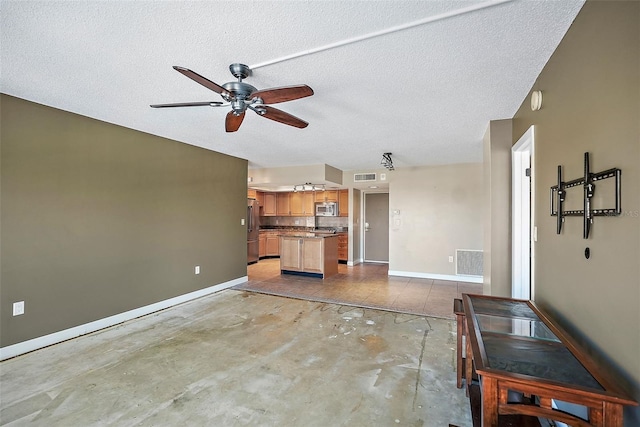 unfurnished living room featuring ceiling fan and a textured ceiling